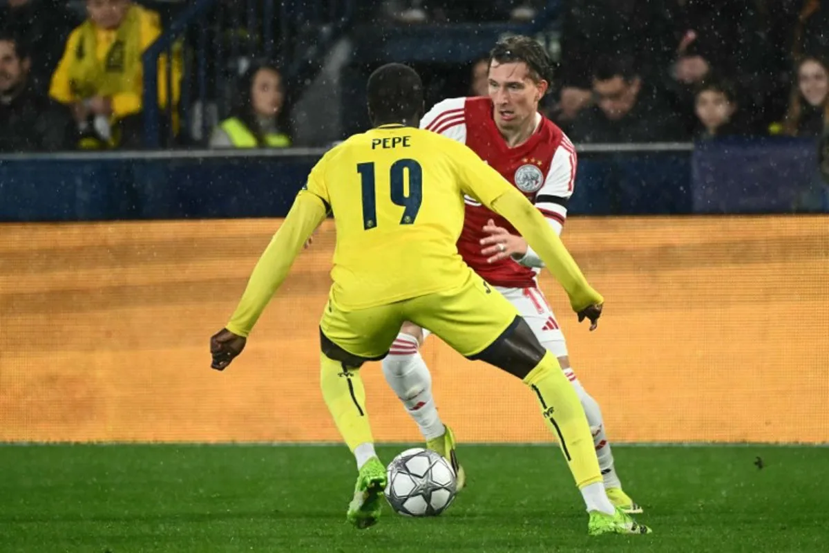 Villarreal's Ivorian forward #19 Nicolas Pepe and Ajax's Belgian forward #11 Mika Godts fight for the ball during the UEFA Champions League league phase day 7 football match between Villarreal CF and Ajax at La Ceramica Stadium in Vila-real on January 20, 2026.  JOSE JORDAN / AFP
