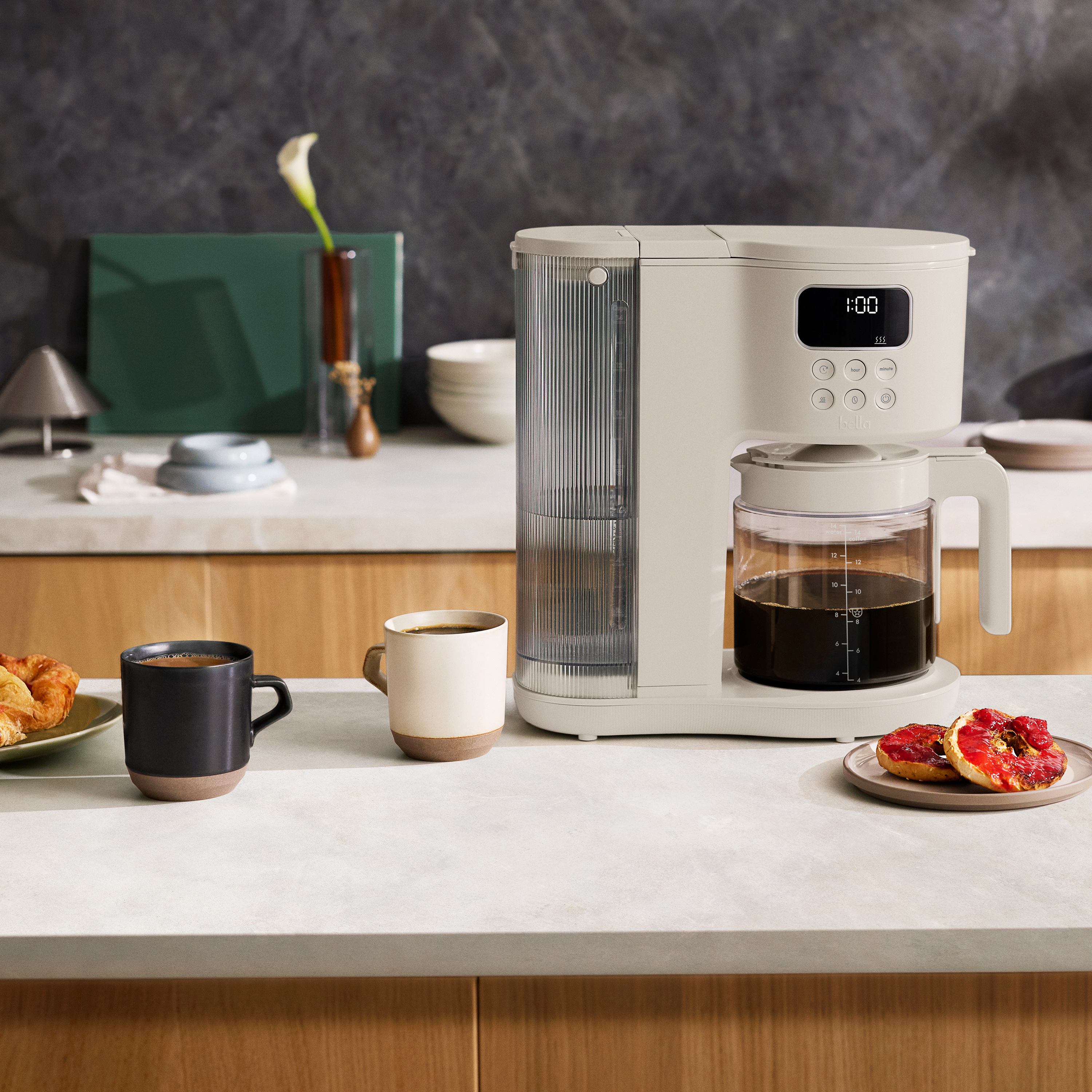 Coffee maker on counter with two cups of coffee beside it.