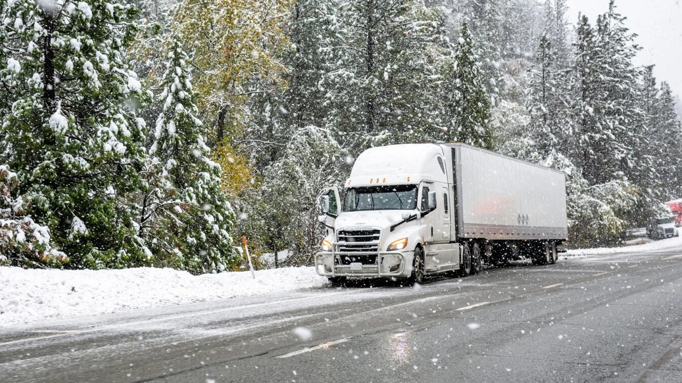 Truck driving on snowy road.
