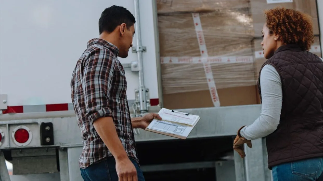 Man and woman having a conversation behind an open truck.