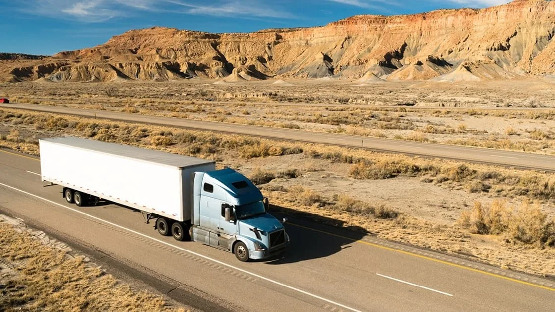 Truck driving on desert road.