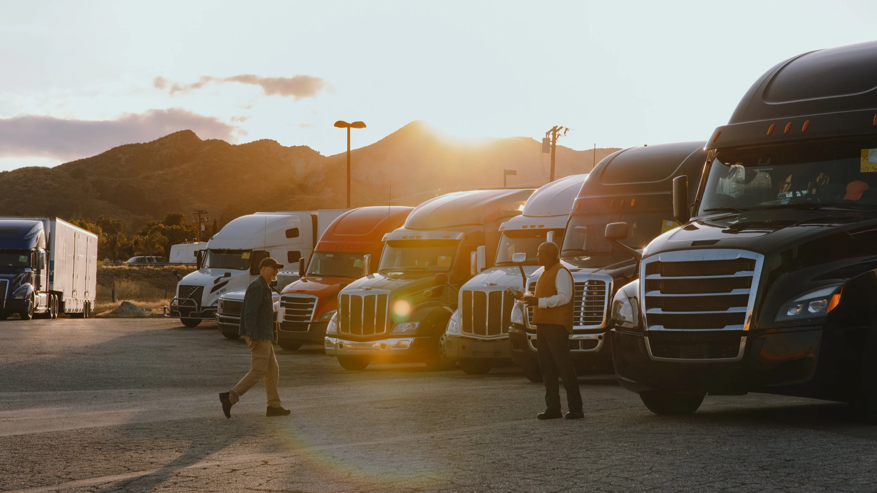 Truck drivers in front of a fleet at sunset