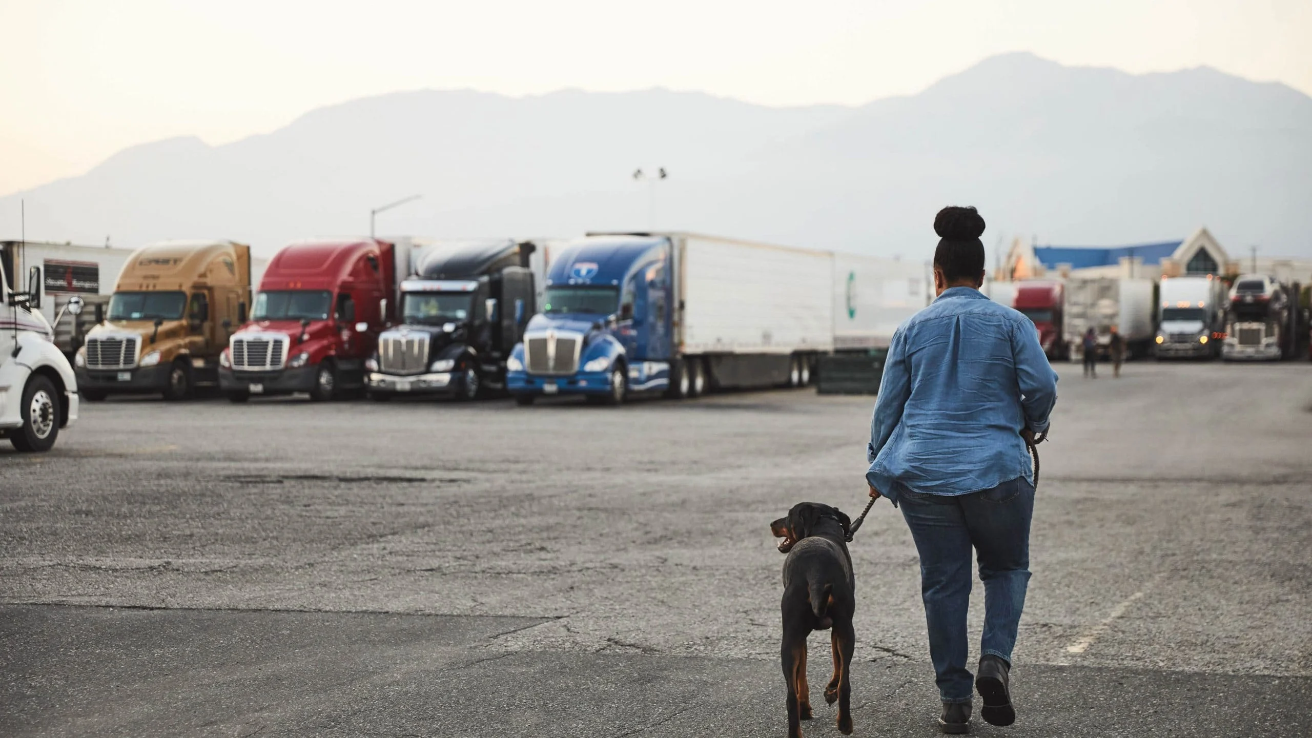 Woman walking dog at truck stop.