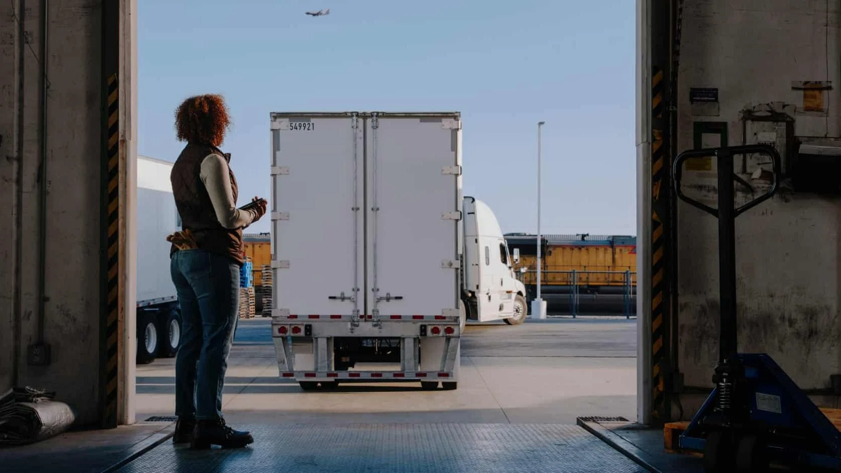 Woman watching truck from loading dock.