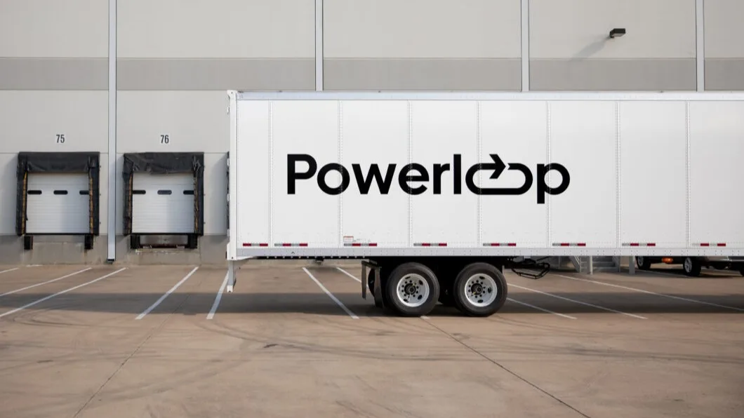 White Powerloop delivery truck parked at loading docks numbered 75 and 76 of a warehouse facility.