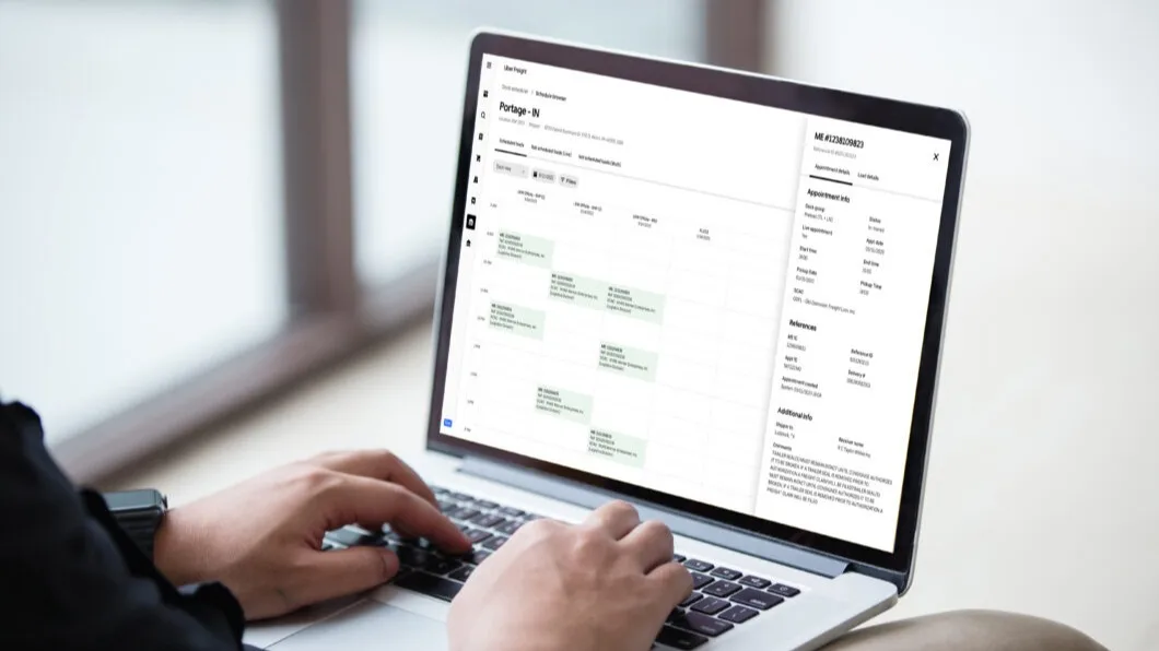 Person using laptop displaying a scheduling interface with appointment calendar and patient information details.
