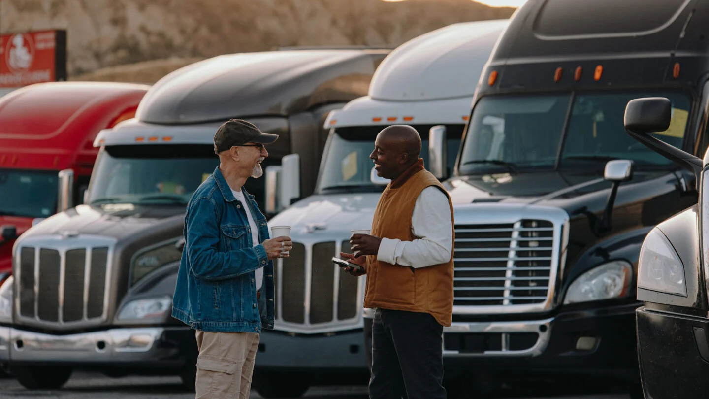 Two men talking in front of a row of trucks.
