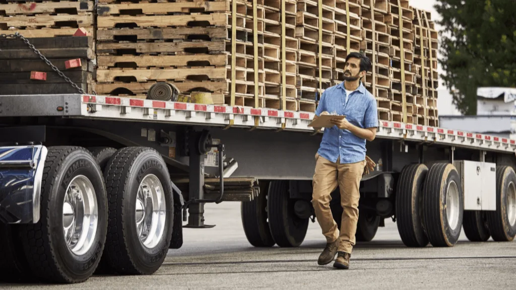 Man walking near truck full of pallets.