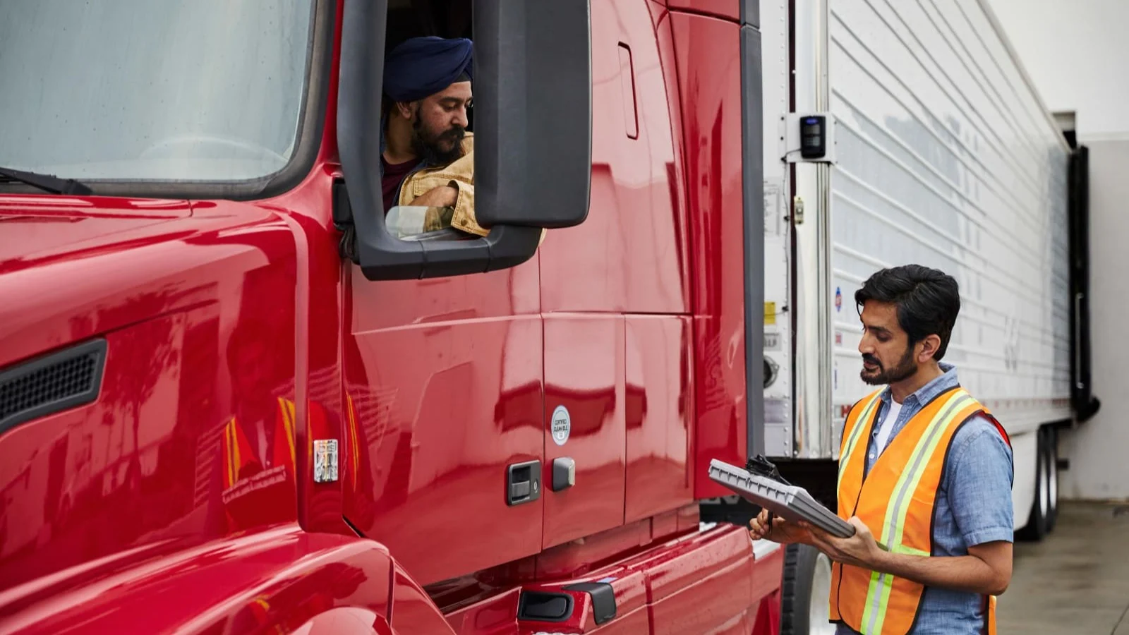 Two men talking through the window of a truck.
