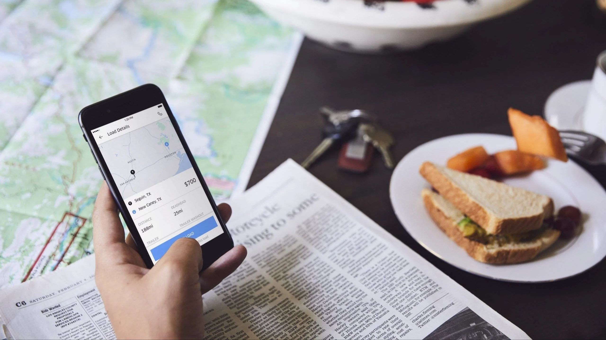 Person holding a phone looking at the Uber Freight shipping software.