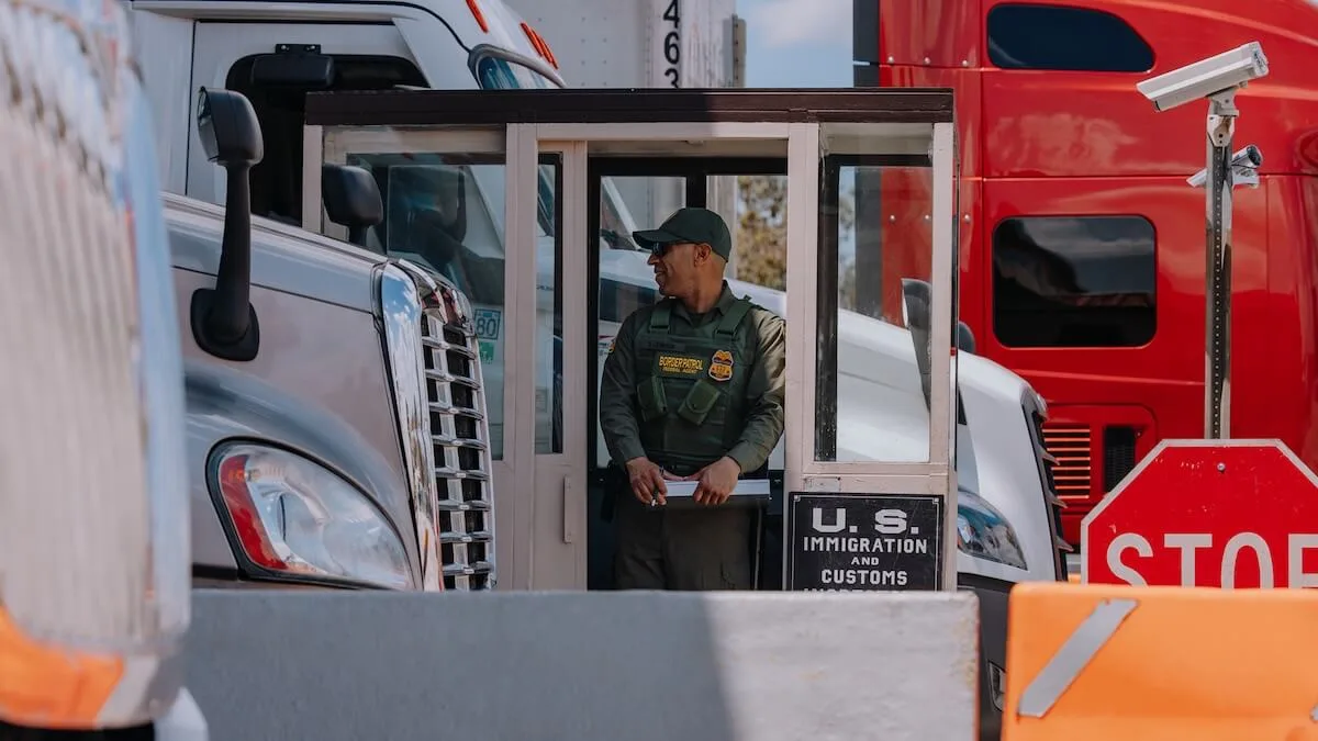Border patrol agent in booth at border inspecting trucks