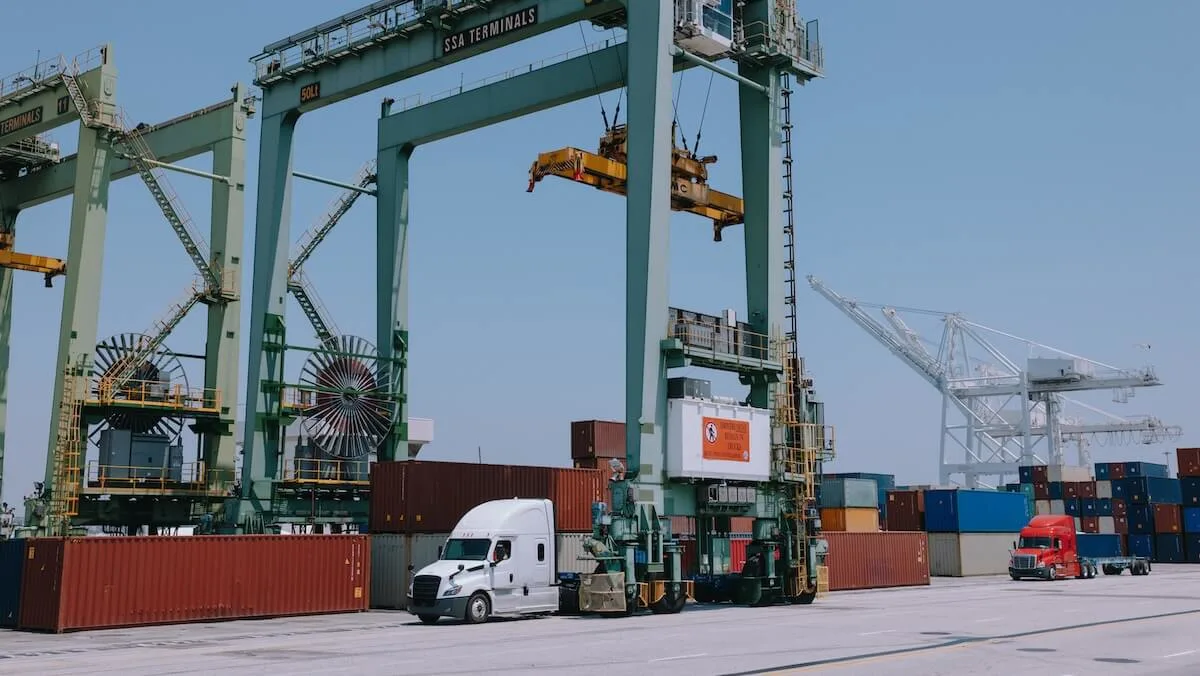 Truck at shipping port being loaded with freight by a large crane