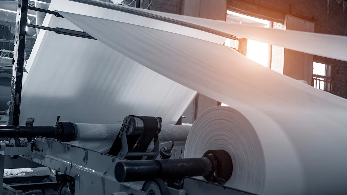 Large rolls of paper moving through an industrial mill, representing a Pacific Northwest paper producer using Uber Freight’s managed transportation.