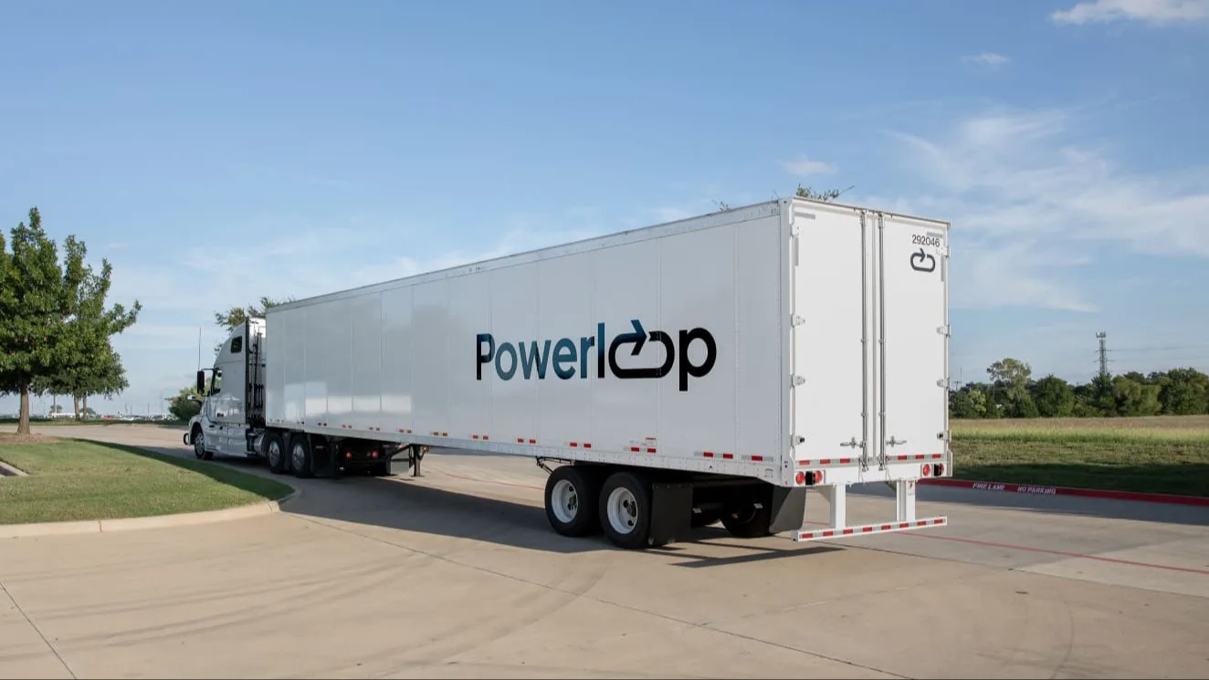 White semi truck with "Powerloop" logo on trailer driving on concrete road under clear blue sky.