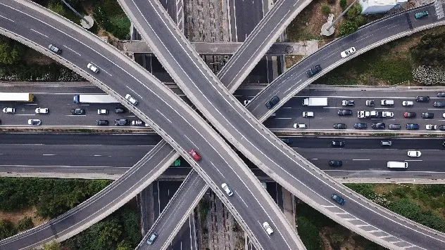 Professional portrait with a blue geometric cube design element against a white and blue background.