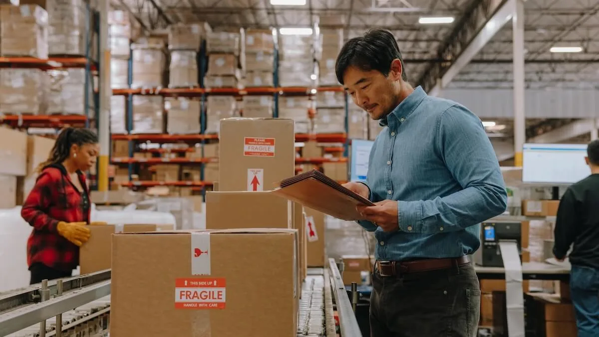 Expéditeur inspectant des colis qui passent sur un tapis roulant dans un entrepôt animé