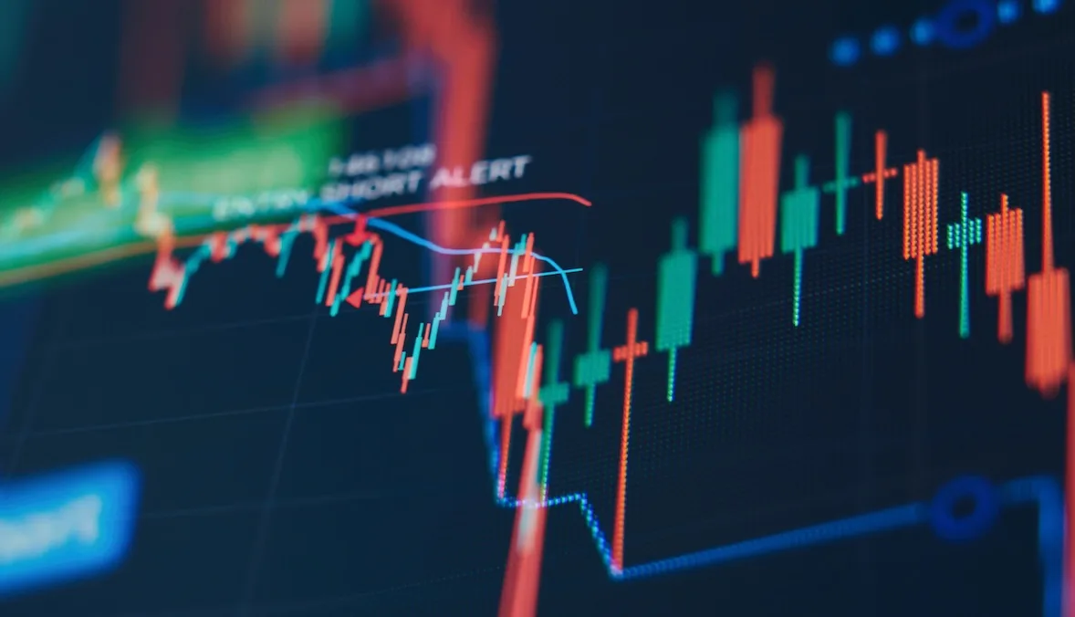 A dark digital display showing fluctuating stock market candlestick charts and trend lines indicating market volatility.