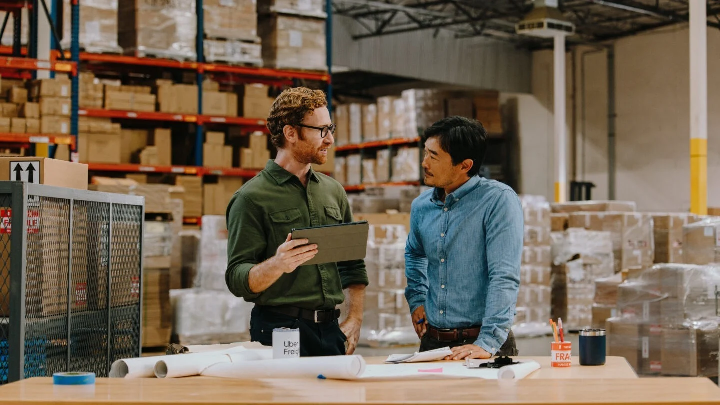 Two men having a discussion in a warehouse.