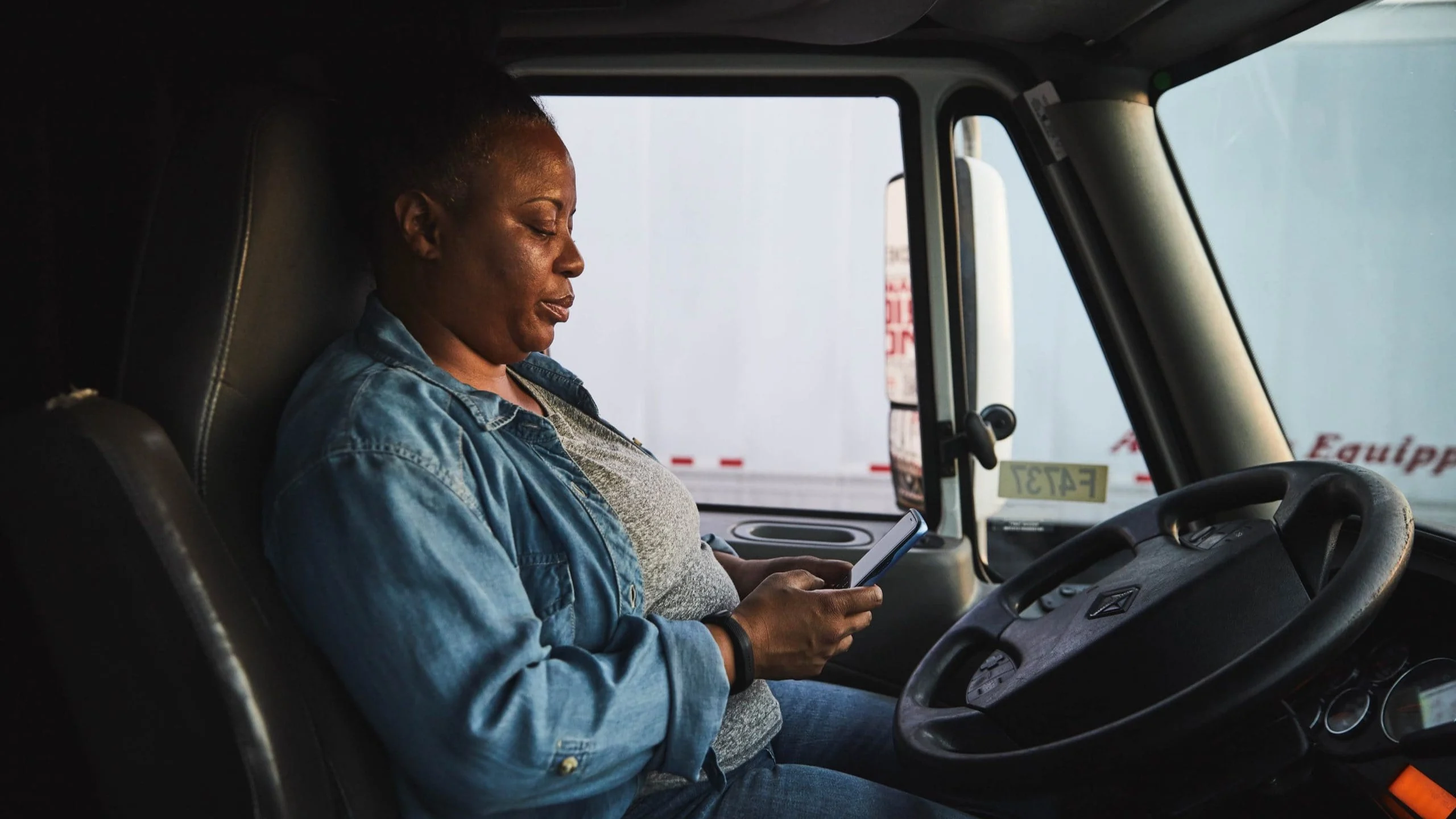 Woman in truck looking at phone.