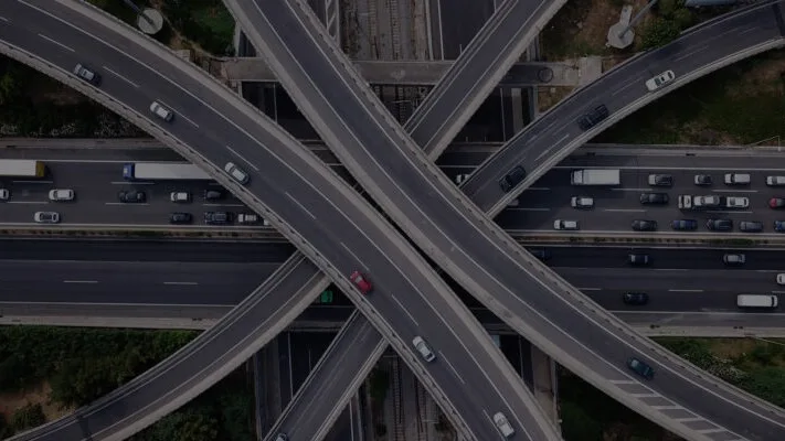 Aerial view of a complex highway interchange with multiple levels of roads crossing and vehicles traveling in different directions.