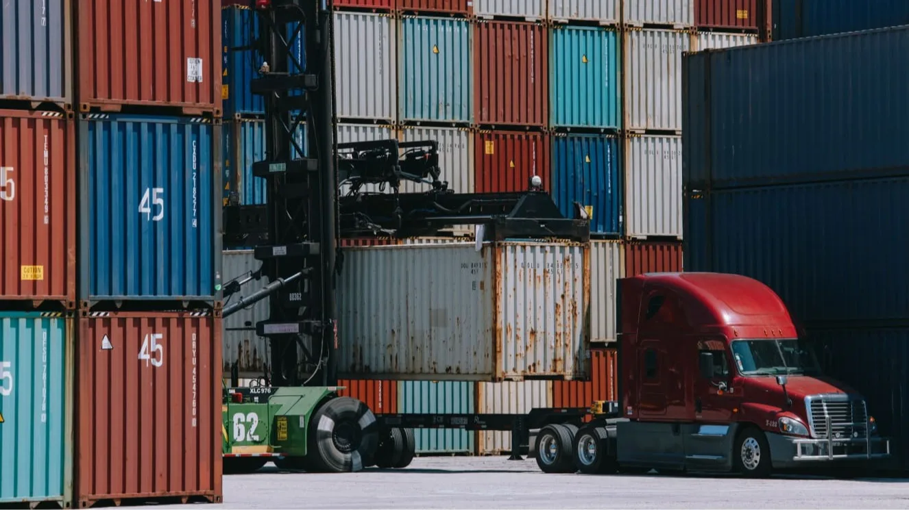 Truck getting loaded with shipping containers.