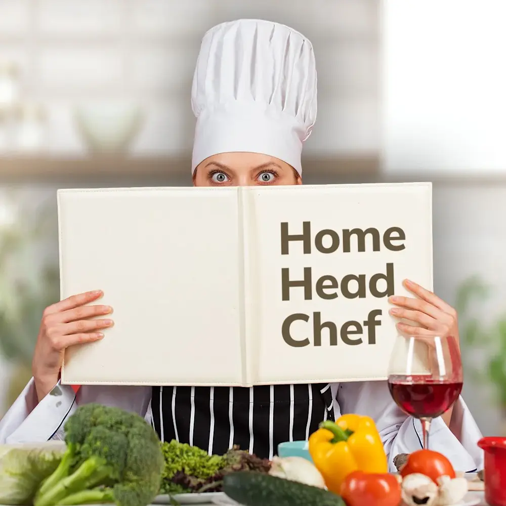 Women holding large book in front of face entitled Home Head Chef