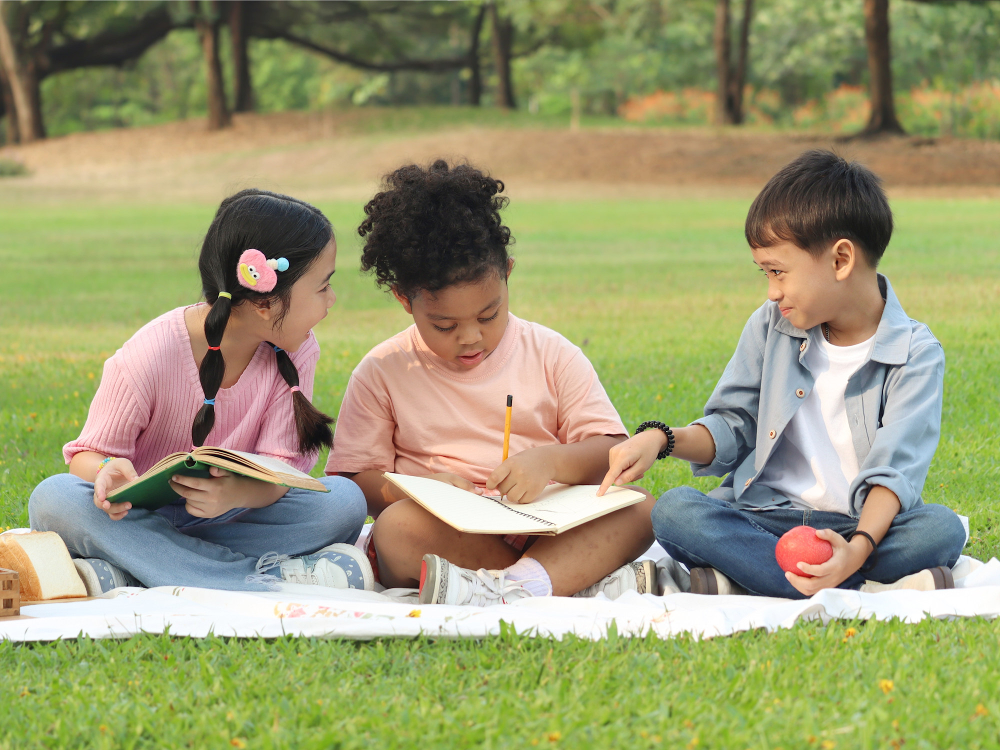 3 kids reading and writing outside together