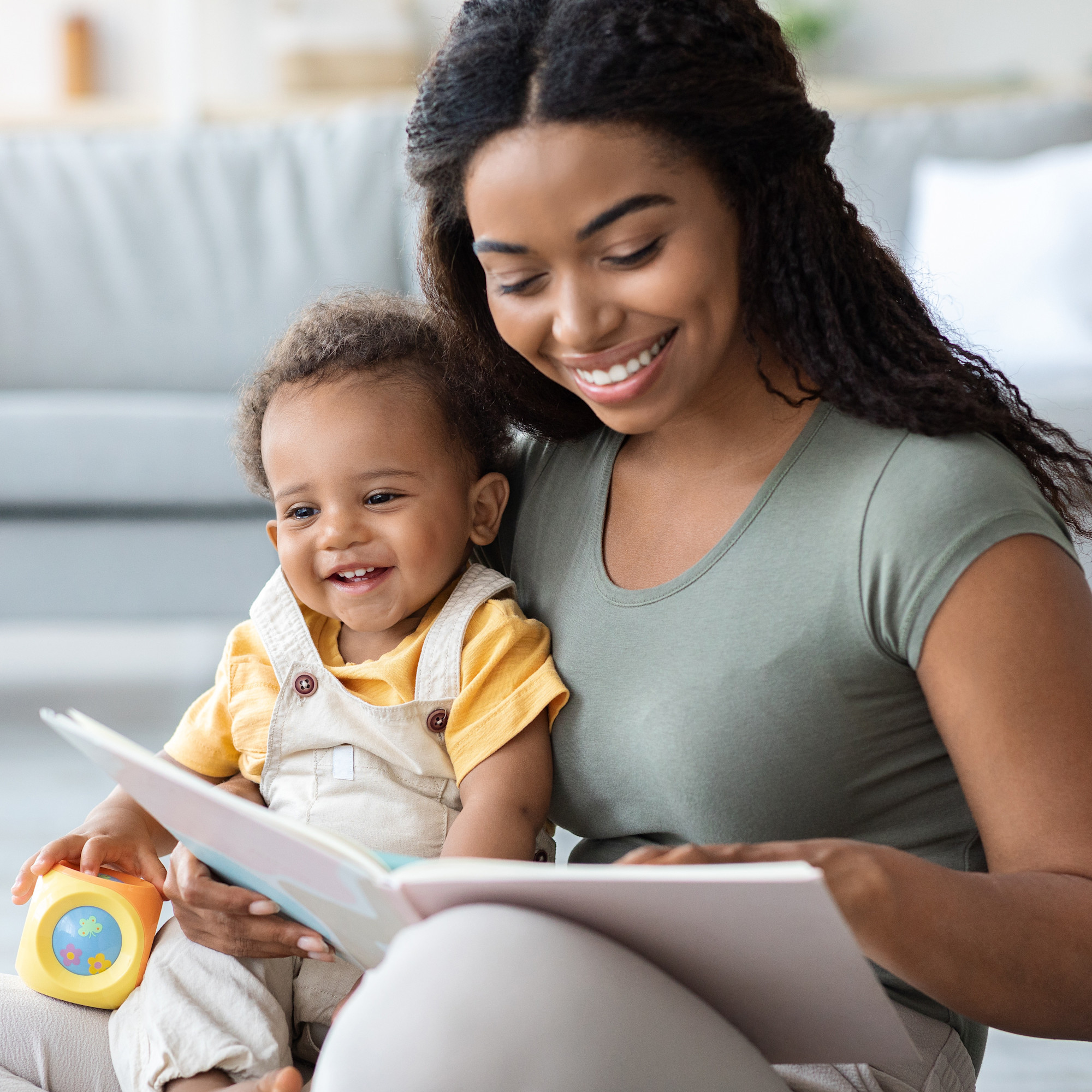Mother and small child sitting on the floor reading a book together