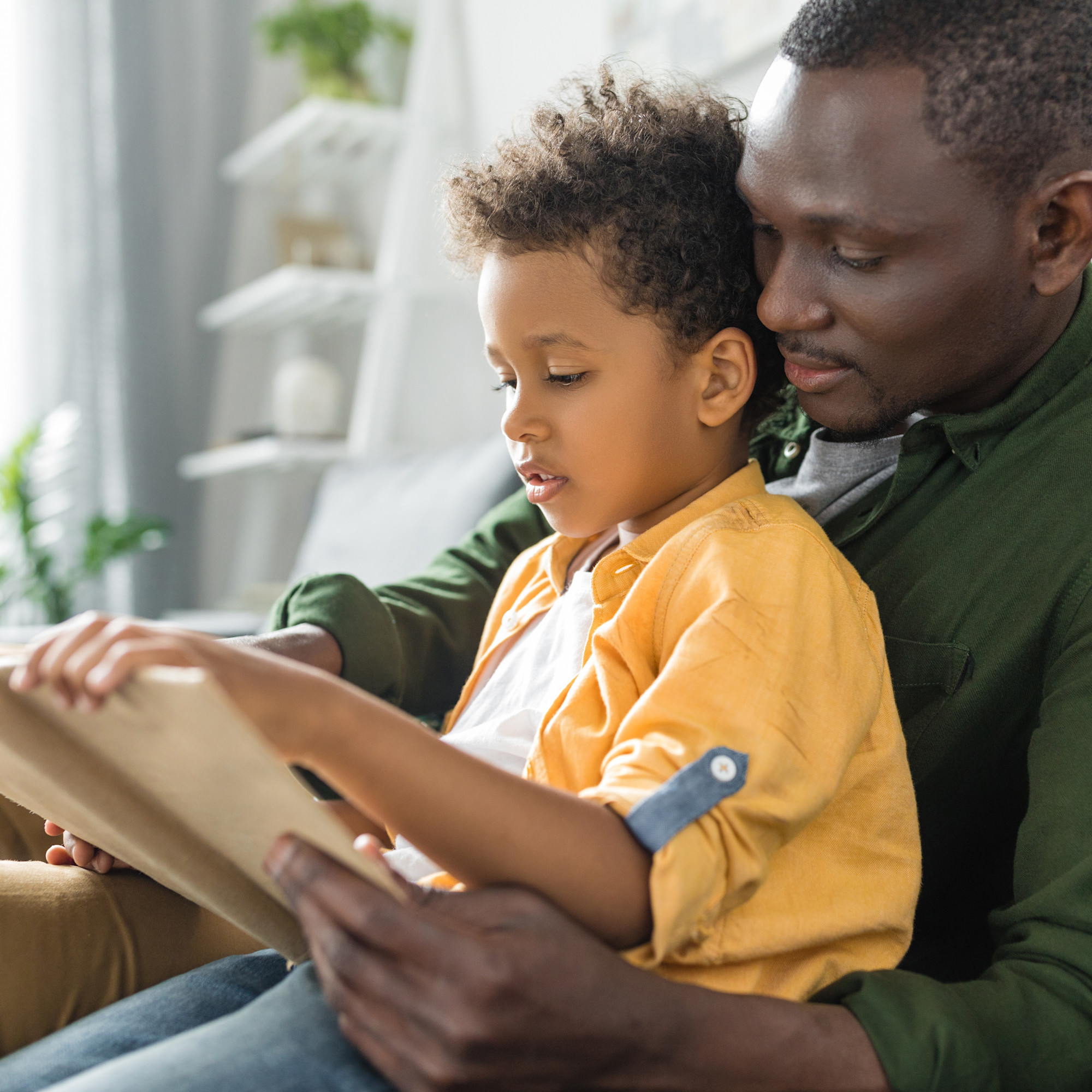 Father and child sitting in chair reading together