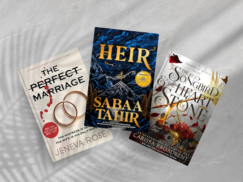 Three Bestsellers of 2025 so far on marble surface: The Perfect Marriage by Jeneva Rose (white cover with wedding rings and red drops), Heir by Sabaa Tahir (dark blue fantasy cover with golden text and award medallion), and The Songbird and the Heart of Stone by Carissa Broadbent (white cover with ornate golden design).