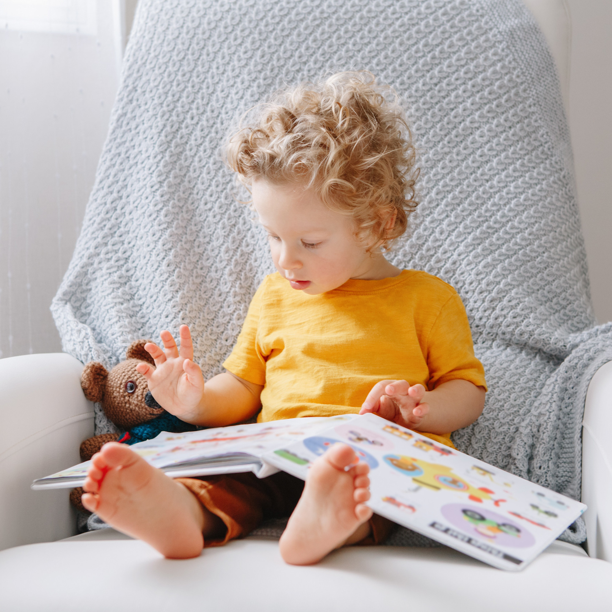 Toddler reading book on chair