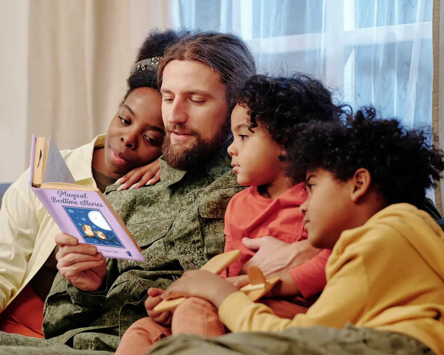 Family enjoying shared reading time together in cozy home setting with bright window lighting promoting literacy and togetherness