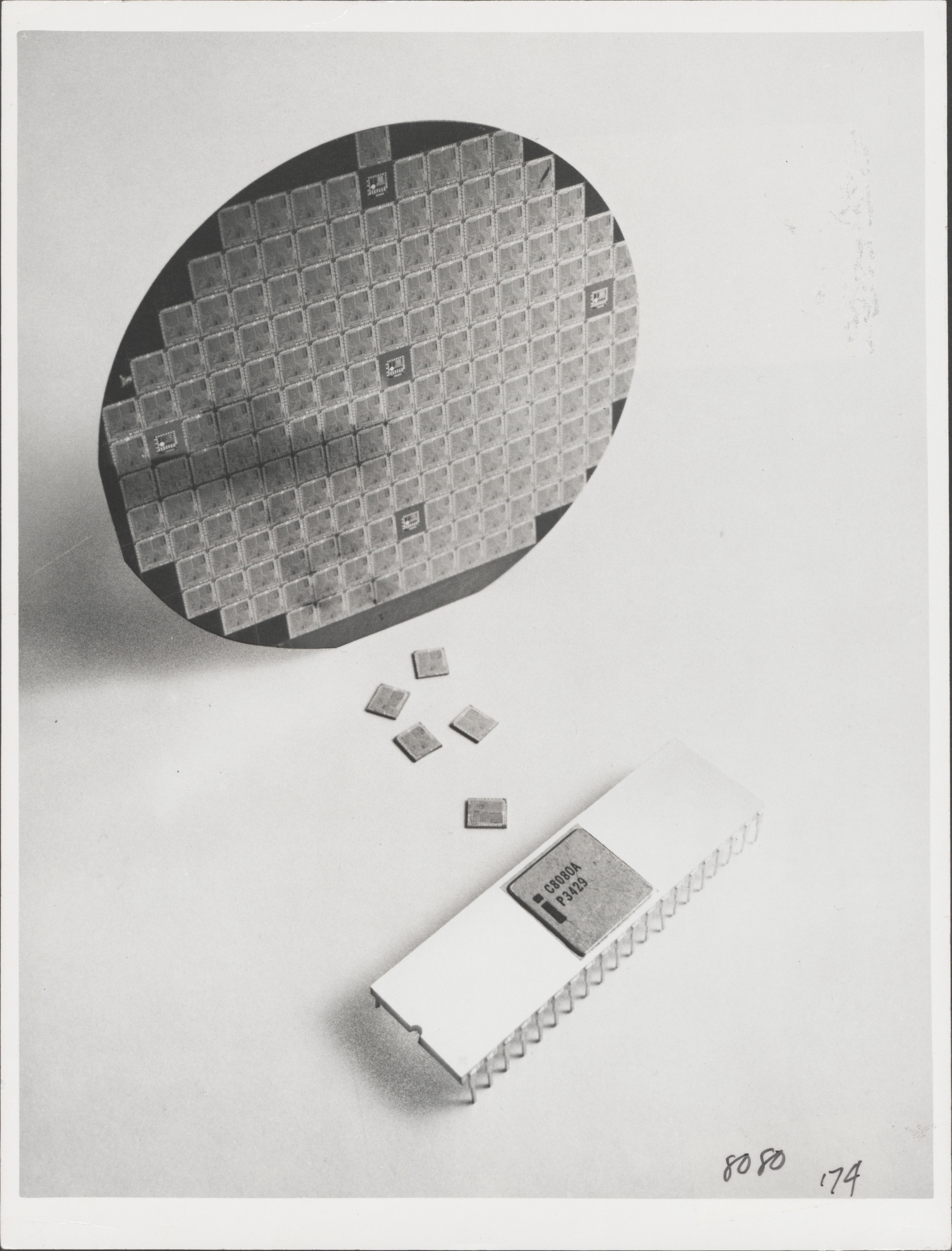 The 8080 in its package, sitting in front of a chip wafer and several loose 8080 chips. 