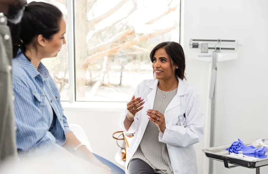 A doctor interacting with a patient seated in an office.