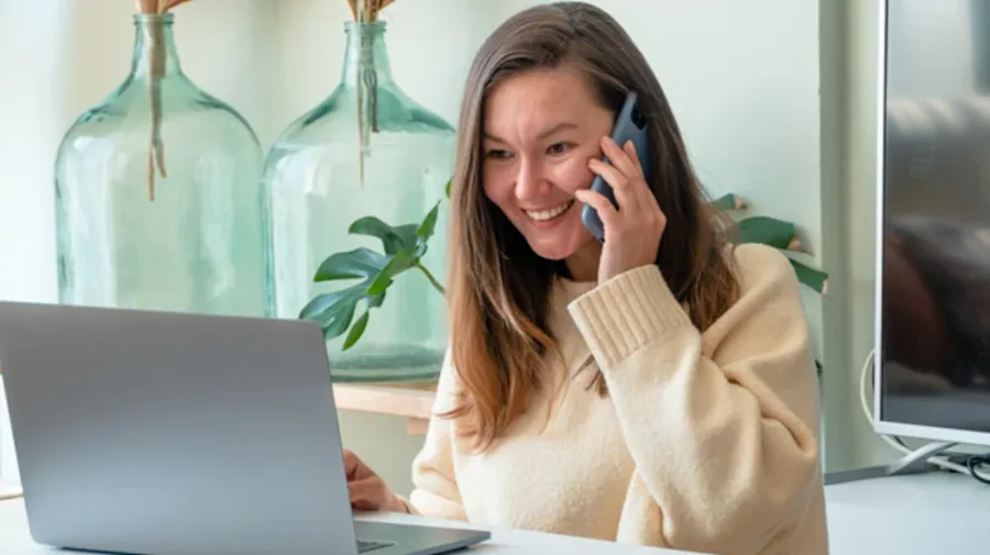Woman on the phone while looking at her computer.