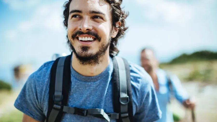 A person smiling while on a hike with friends. 