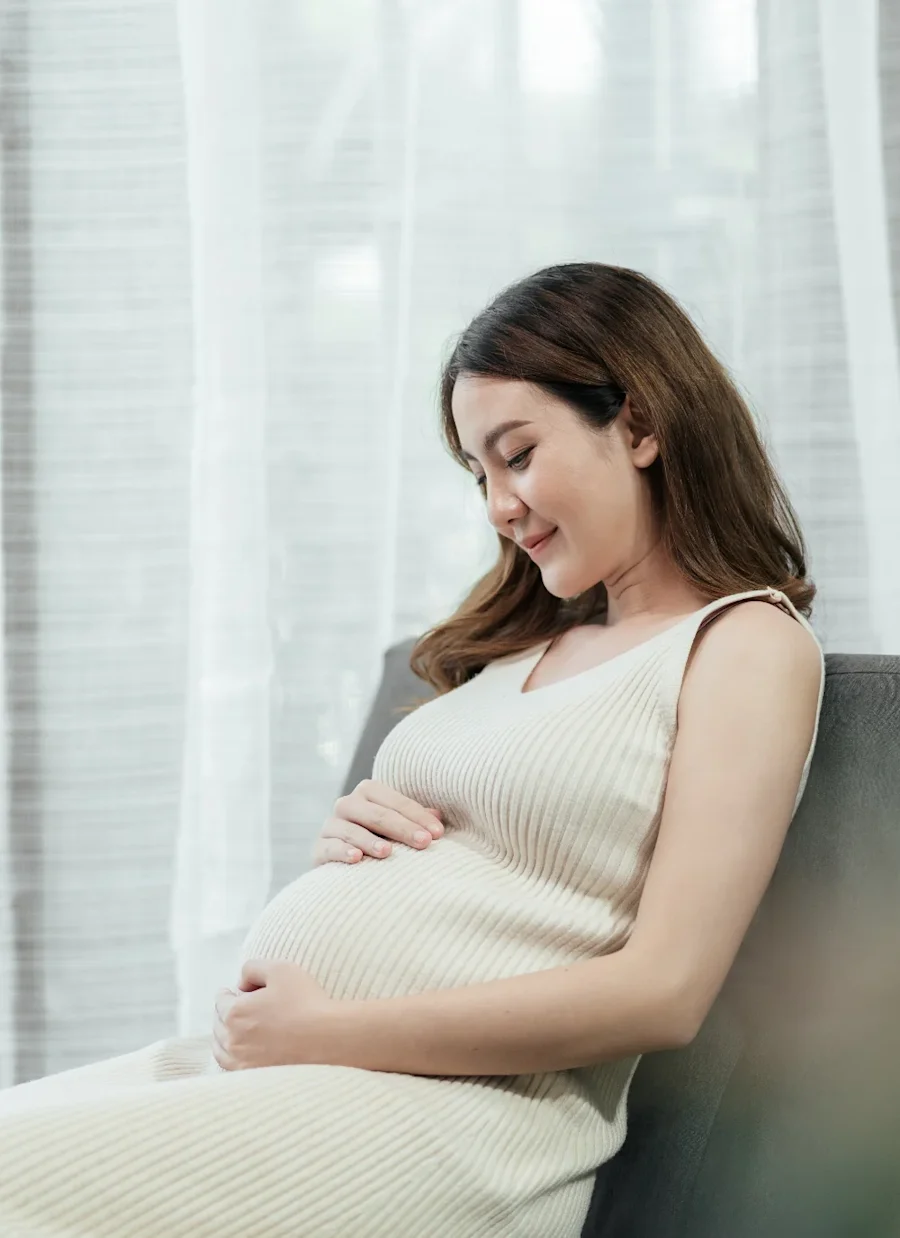 A pregnant person seated while smiling.