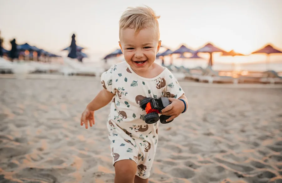 A child walking on a beach, smiling.