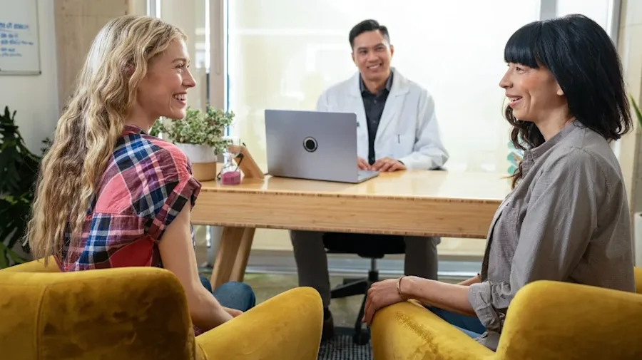 Two females smiling, discussing with a doctor.