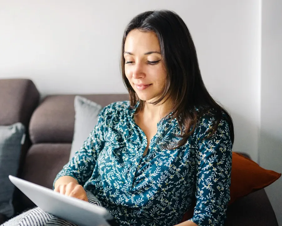A person seated on a couch interacting with a tablet.