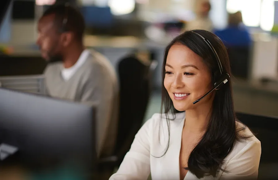 Two people working in a call center, smiling.