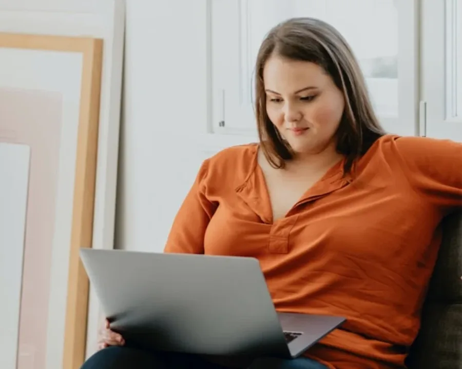 A person smiling while interacting with a laptop.