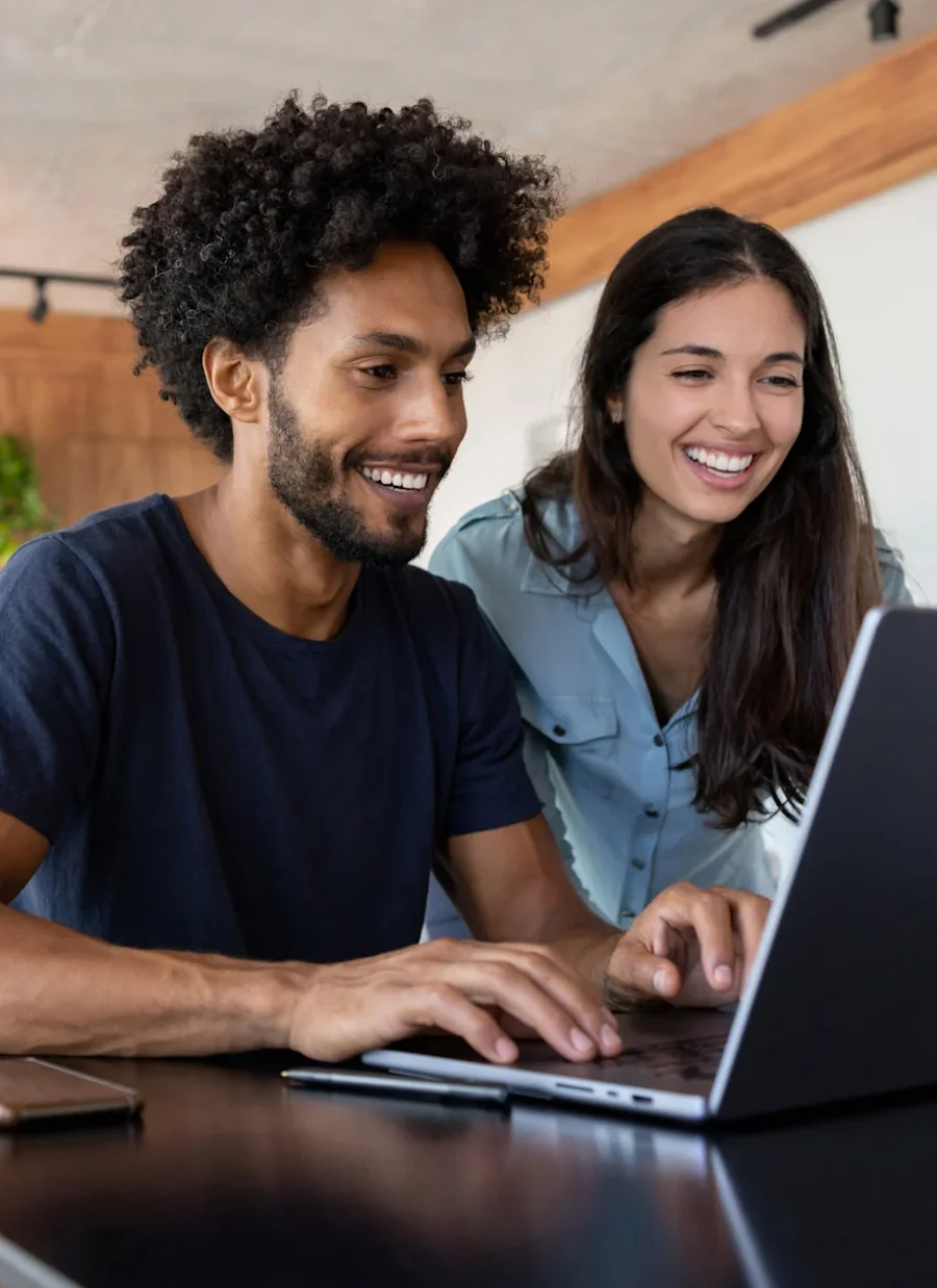 Male and female smiling, interacting with a laptop. 