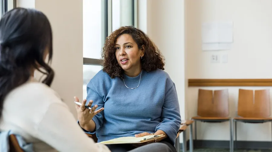 Two people having a conversation while seated in a medical office. 
