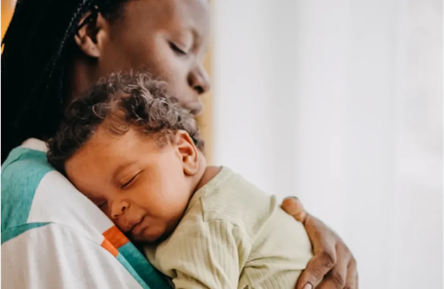 A baby sleeping on a parent's shoulder.