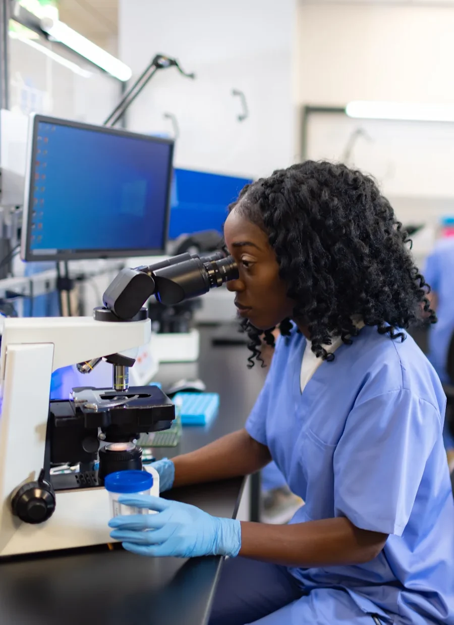 A female looking through a microscope in a lab.