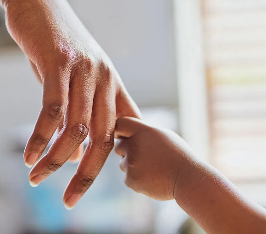 Child's hand holding the index finger of their parent.