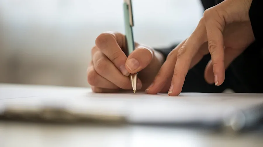 Person writing with a pen on paper. 
