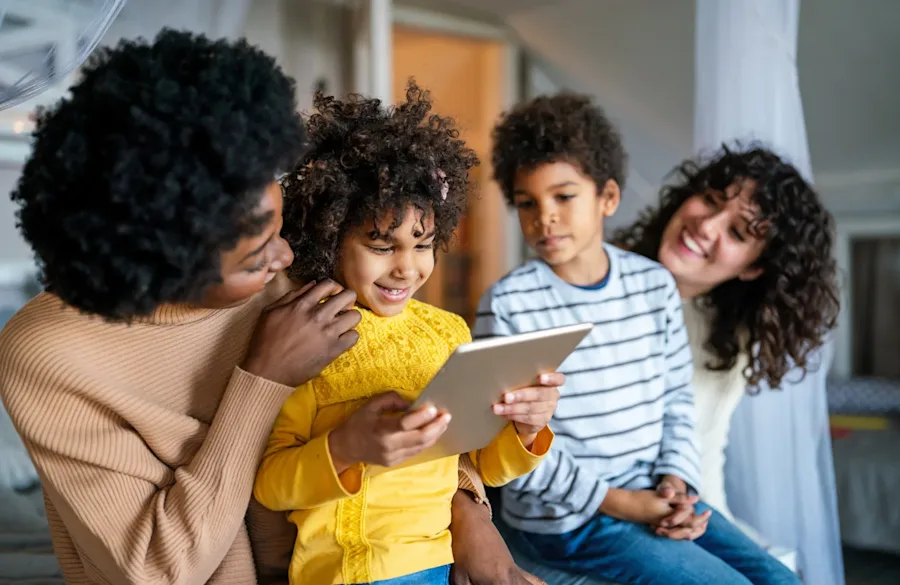 A family smiling together while a child holds a tablet.