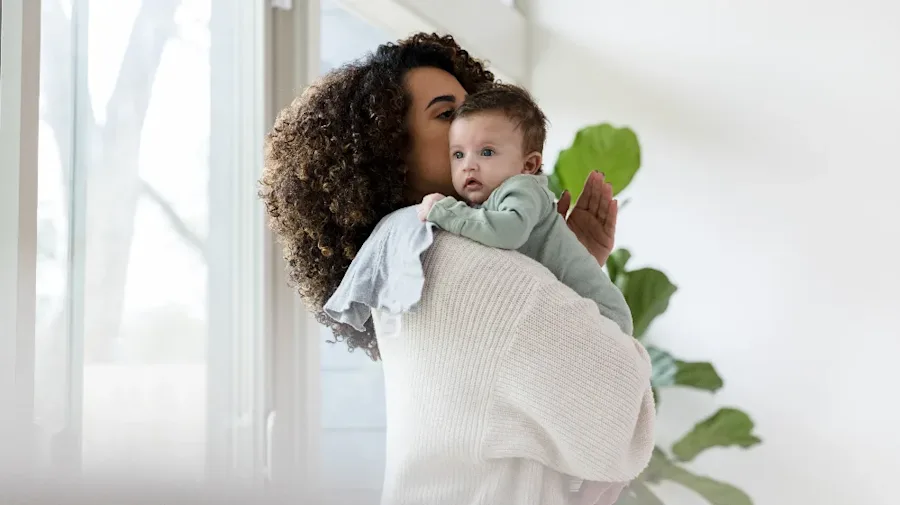 A female holding a child while standing. 